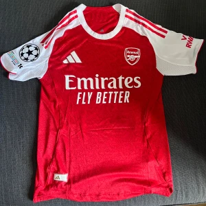 Gyökeres Arsenal Matchtröja - Säljer nu denna Gyökeres tröjan! Tröjan är aldrig använd så den är i ett perfekt skick. Den har storlek M men passar även S. Original förpackningen och prislappen finns kvar! Tröjan har även UEFA Champions League logan på axeln. Skick: 10/10 Nypris: Ca 1000kr
