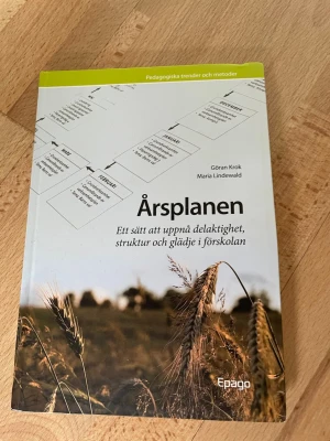 Årsplanen för förskolan - Boken 'Årsplanen' av Göran Krok och Maria Lindewald ger konkreta tips och metoder för att skapa struktur, delaktighet och glädje i förskolan. Omslaget är vitt och grönt med motiv av åker och schema. Perfekt för dig som pluggar pedagogik eller jobbar inom förskola.