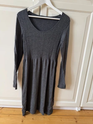 Mörkgrå stickad klänning Esprit - Mysig mörkgrå stickad klänning från Esprit med rund halsringning och ribbad överdel. Klänningen har lång ärm och är i mjukt material. 