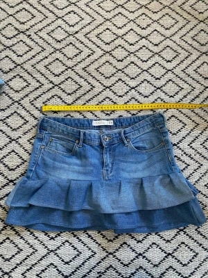 Blå jeanskjol med volang från Lindex - Snygg blå volang kjol från Lindex, som är om syd från jeans till kjol. Kjolen är kort och har en normal passform. Skriv för mer och bättre bilder!💗