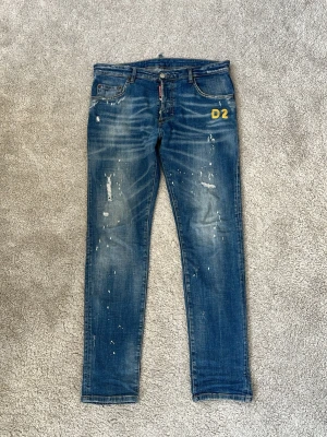 Dsquared2 jeans - Hej! Säljer dessa riktigt feta detaljrika Dsquarred2 jeans med tillgjorda slitningar, färgstänk, tvätt och sydd text från design! Jeansen är slim fit, tillverkade i Italien och är i ett mycket gott skick förutom en liten slitning/hål i skrevet. Går väldigt enkelt att sy ihop. (Jag kan lösa det efter köp men då är priset inte förhandlingsbart). Nypriset ligger på runt 4000kr! Jeansen är autentiska! Varmt välkommen att höra av dig till mig vid minsta intresse av köp! 😁Mvh DS 