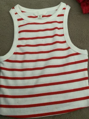 Vit och röd randig ribbad crop top - Säljer en ribbad crop top med vita och röda horisontella ränder. Toppen har breda axelband och rund halsringning, perfekt för en avslappnad och trendig look. Materialet är mjukt och stretchigt för extra komfort. Toppen har aldrig varit använd men saknar prislapp❣️