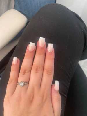 Pandora silverring med hjärta - Säljer en stilren silverring från Pandora med ett gnistrande hjärta i mitten. Ringen har en tunn banddesign med små stenar längs sidorna som ger extra bling. Perfekt för dig som gillar romantiska detaljer och klassisk look. Kommer i original ask från Pandora.