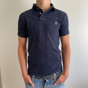 Mörkblå Pike från Polo Ralph Lauren - Säljer en mörkblå pikétröja från Polo Ralph Lauren med broderad logga på bröstet. Perfekt inför sommaren! 🏖️ Tröjan är i Slim Fit model i storlek S. Modellen är 178cm lång. Tveka inte på att skriva om du har funderingar!🤩 Priset är inte hugget i sten 🪨 