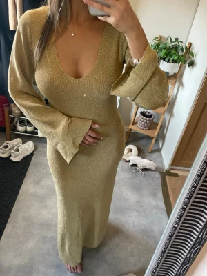 Guldig långklänning - Säljer en glittrig guldig långklänning med djup v-ringning och vida ärmar🫶🏼