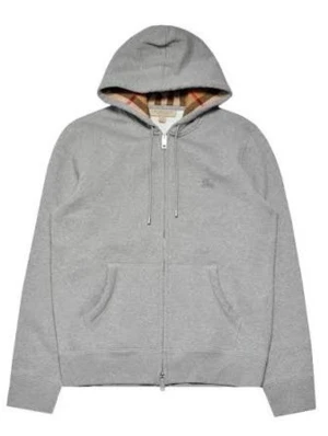 Grå zip hoodie från Burberry - Snygg grå zip hoodie från Burberry med klassiskt rutigt foder i huvan och diskret logga på bröstet. Hoodien har dragsko i huvan, två fickor fram och ribbade muddar. Perfekt för en avslappnad och trendig look.