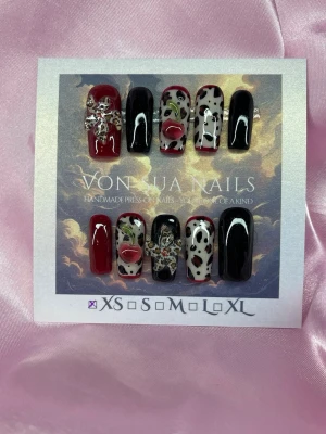 WildCherry (XS);Medium Square;Curved - Unika press-on naglar i storlek XS: 14 mm, 11 mm, 11,5 mm, 10 mm, 8 mm. Setet har en mix av svart, vinrött och vitt med coola leo-mönster, 3D-dekorationer som leo-blomma och röda körsbär. Naglarna är medium långs och har en glansig finish, perfekta för dig som vill sticka ut.