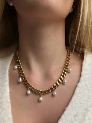 Guldigt 9mm bred halsband med droppformade pärlor - Presentask ingår. Det finns möjlighet att köpa utan preesentask till ett lägre pris (se en annan annons på min sida).   Matchande örhängen finns i en separat annons  Finns även i silverfärg   Material: 18K guldplätering på rostfritt stål Bredd: 9 mm Längd: 38-43cm Nickelfria och handgjorda. Märke: Diavansa smycken