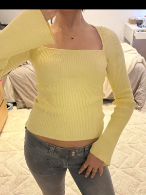 Gul ribbstickad tröja med utsvängda ärmar -  ljusgul ribbstickad tröja med fyrkantig ringning och långa utsvängda ärmar. 