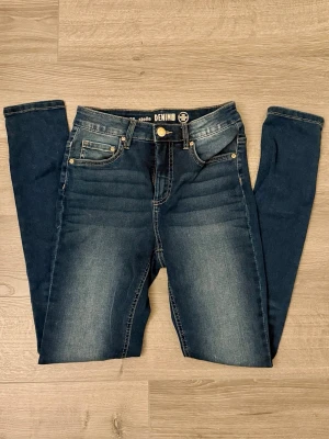 Mörkblå skinny jeans Stella Denim - Snygga mörkblå skinny jeans från Stella Denim med klassisk femficksmodell och guldfärgade detaljer. Jeansen har en lätt tvättad look med slitningar framtill och är tillverkade i stretchigt denimtyg för skön passform.