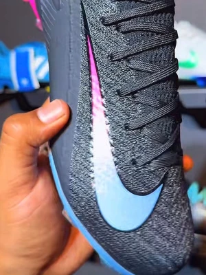 Nike Mercurial svart/blå fotbollssko - Snygg fotbollssko från Nike Mercurial-serien i svart med blå Swoosh och rosa detaljer vid hälen. Ovandelen är i stickat syntetmaterial för bra passform och känsla på bollen. Skon har snörning och en modern, sportig design som sticker ut på planen.