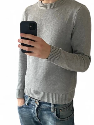 Grå stickad tröja från Dobber | Medium - Snygg grå stickad tröja från Dobber med rund halsringning och ribbade muddar vid ärmslut och nederkant. Perfekt för lager-på-lager och enkel att matcha med jeans eller chinos. Materialet känns mjukt och bekvämt.