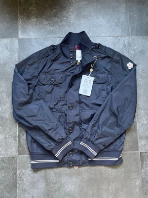 Moncler field jacka  - Tjena, säljer nu denna riktigt snygga och populära Moncler fieldjackan, den är i mycket bra skick utan några skador, storlek 1 motsvarar Small, äldre model, hör av er vid frågor och funderingar🙌🤝 