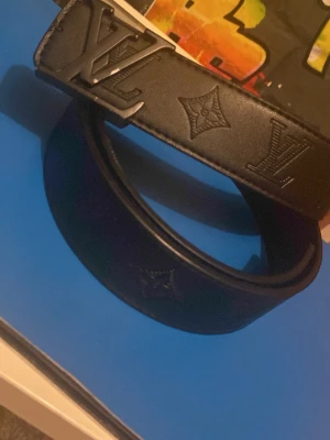 Svart Zara läderbälte - Snyggt svart bälte från Zara  i läder med klassisk zara logga i metall på spännet och präglade monogramdetaljer längs remmen. Perfekt accessoar för att lyfta din outfit med en exklusiv touch. Milda skador. Pris kan diskuteras!