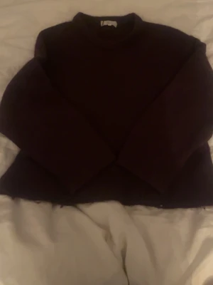 vinröd/mörk lila stickad tröja - Mysig mörkbrun stickad tröja med rund halsringning och långa ärmar. Perfekt för kyliga dagar och enkel att matcha med jeans eller kjol. Tröjan har en rak passform och ser ut att vara tillverkad i ett mjukt material.
