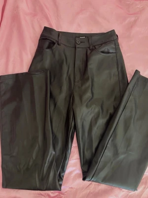 Leather straight leg black pants ( S-M) - Mycket bra skick, säljes då de är för stora för mig. Svarta faux leather-byxor med raka ben och smickrande hög/mellanmidja. Mjukt material med en stilren läderlook som lyfter vilken outfit som helst. Lätta att klä upp med klackar eller styla mer casual med en oversized jacka. Perfekt basplagg för en chic dark feminine-garderob. Storlek S/M. ❤️ Very good condition. Black faux leather pants with a straight leg fit and flattering high/mid waist. 