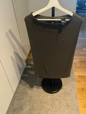 Mörkgrön ärmlös klänning H&M - En enkel och stilren mörkgrön klänning från H&M. Klänningen är ärmlös med rak passform och mjukt, stretchigt material som ger en bekväm känsla. Perfekt att styla med accessoarer för en personlig look.