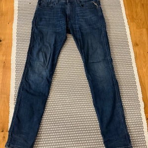 Replay Anbass jeans mörkblå  - Säljer ett par snygga Replay Anbass jeans i mörkblå tvätt. Modellen har smal passform, klassiska fem fickor och diskreta slitningar. Jeansen är tillverkade i stretchig denim för extra komfort och har Replay-logga på bakfickan.