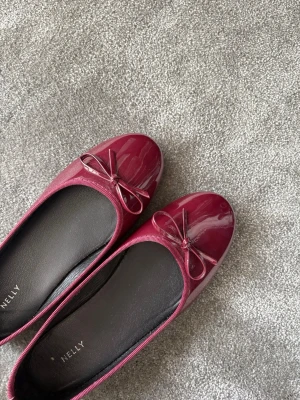 Vinröda ballerinaskor - Vinröda ballerinaskor, glansiga från Nelly. Är lite mörkare i verkligheten.
