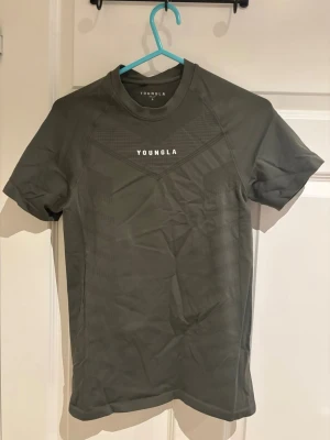 475 supervillan compression t-shirt från YoungLA - Snygg olivgrön t-shirt från YoungLA med diskret mönster och logga på bröstet. T-shirten har rund hals och korta ärmar, perfekt för en sportig och avslappnad stil. Materialet känns mjukt och följsamt mot kroppen. 