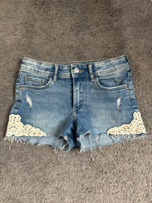 Jeansshorts H&M - Snygga blå jeansshorts med spets kanter. Bra skick har använts men har inga defekter. Storlek 140 men passar fortfarande mig bra som är 158.