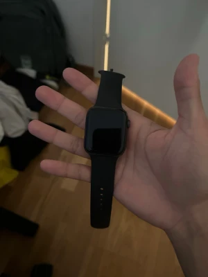 Svart Apple Watch med silikonarmband - Snygg svart Apple Watch med fyrkantig skärm och svart silikonarmband. Klockan har en stilren design med digital krona på sidan och pulssensor på baksidan. Perfekt för dig som vill ha koll på notiser, träning och hälsa direkt på handleden. Laddare kommer med!!