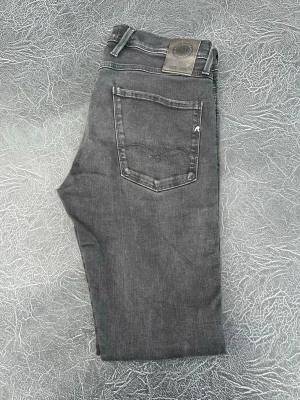 Svarta jeans från Replay - Snygga svarta Jeans från Replay med klassisk femficksdesign och diskret logga på bakfickan. Jeansen har raka ben och är tillverkade i en mjuk bomullsblandning med lite stretch för extra komfort. Perfekta för en avslappnad och trendig look. Storlek W 32 L 32