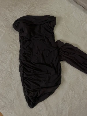 Svart noshoulder kortklänning - Aldrig använd . Har ett jätte fint tyg som hänger ner på klänningen 