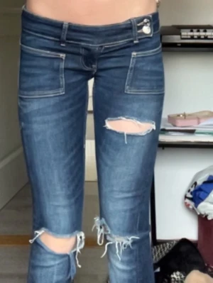 Mörkblå slitna jeans med hål - Säljer ett par mörkblå jeans med slitningar och stora hål vid knäna och låret.  De e lågmidjade och lite sönder längst ner men inget man märkt av. Dyrare pris då den är slutsåld i denna storleken 