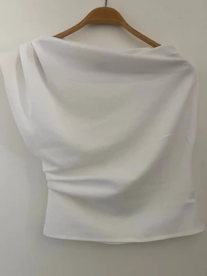 Superfin topp - Stilren vit one-shoulder topp. Superfint material och i nyskick!  Knappt använd av tidigare ägare och endast testad av mig. Köpt på Vinted.  Köptes för 150 kr.   Storlek S.  Skickar snabbt📦  Vid frågor eller mer info – hör gärna av dig🫶🏼