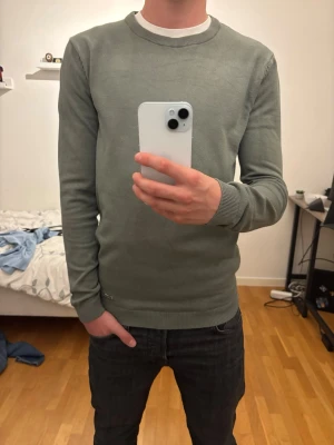 Grön stickad tröja från SAMS - Snygg grön stickad tröja från SAMS med rund halsringning och ribbade muddar vid ärmslut och nederkant. Enkel och stilren design som passar perfekt till jeans eller chinos. Skön och lätt att bära, perfekt för lager-på-lager. Ord pris 300kr. Endast använd en gång. 