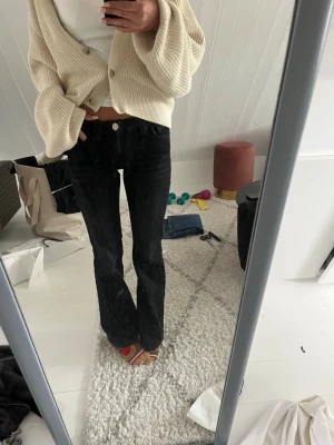 Svarta bootcut jeans från Gina Tricot - Säljer ett par svarta bootcut jeans från Gina Tricot. Jeansen har hög midja, klassisk femficksmodell och lätt stretchigt material för skön passform. Snygg tvättad look och silverfärgad knapp framtill. Perfekta till en avslappnad stil.