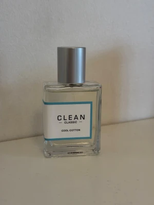 CLEAN Classic Cool Cotton parfym - Fräsch parfym från CLEAN i doften Cool Cotton. Flaskan är rektangulär i genomskinligt glas med en stilren etikett i vitt och blått. Locket är silverfärgat och cylindriskt. Perfekt för dig som gillar rena och lätta dofter.
