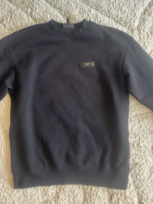 Svart sweatshirt från HM - Stilren svart sweatshirt från Acyphoric med rund halsringning och diskret logga på bröstet. Tröjan har en klassisk passform och är tillverkad i mjukt bomullsmaterial. Perfekt för en avslappnad och trendig look.