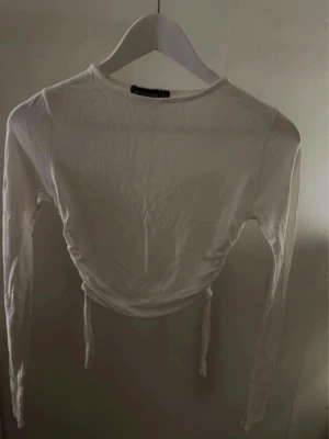 Vit croppad långärmad topp PrettyLittleThing  - Säljer en vit croppad topp med långa ärmar och snörning i sidan. 