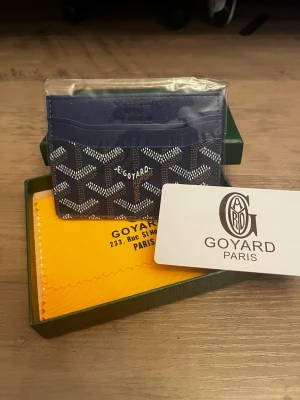 G plånbok - Säljer en elegant blå plånbok i klassisk design med ikoniskt mönster. Perfekt för dig som vill ha en stilren men samtidigt lite mer iögonfallande accessoar till vardags.  Plånboken är helt ny och oanvänd, i toppskick. Smidig storlek men med plats för kort och sedlar.