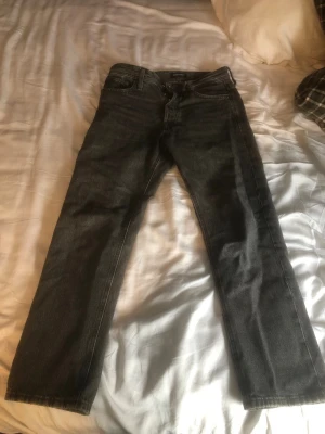 jack&jones jeans 27/30 - Säljer ett par gråa jeans med rak passform och klassisk femficksdesign. Jeansen har normal midja och är tillverkade i ett robust denimtyg. Perfekta för en avslappnad och stilren look. pris ej hugget i sten!!