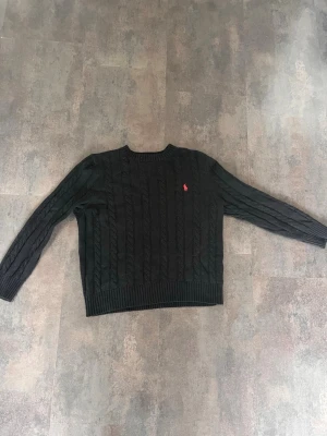 Svart kabelstickad tröja Polo Ralph Lauren - Kabelstickad mörkblå tröja från Polo Ralph Lauren. Har storlek M men sitter som en S då den är lite kort i längd