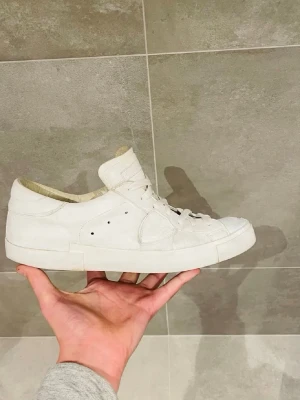 Vita Philippe models BOX FINNS - Stilrena vita sneakers från Philippe Model med klassisk låg siluett. Skorna har vita snören, diskreta sömmar och perforerade detaljer på sidan. Tillverkade i läder med en bekväm innersula och robust yttersula. Perfekta för en clean och modern look.