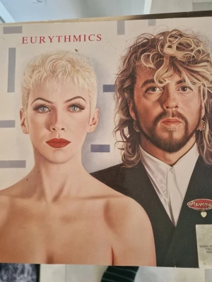 Eurythmics Revenge vinylskiva - Säljer ett vinylalbum med Eurythmics, 'Revenge'. Omslaget har ett konstnärligt porträtt i färg med grafiska detaljer och låtlista på baksidan. Perfekt för dig som gillar 80-talsmusik och samlar på LP-skivor. Inga repor.