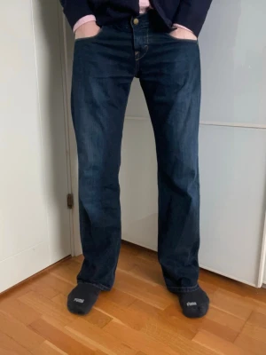 Mörkblå raka jeans från Lee - Snygga mörkblå jeans från Lee med raka ben och klassisk femficksmodell. Jeansen har kontrastsömmar och en diskret Lee-logga på bakfickan. Tillverkade i slitstark denim som ger en cool och tidlös look.