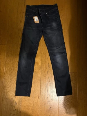Mörkblå slim fit jeans från Tiger of Sweden - Snygga mörkblå slim fit jeans från Tiger of Sweden med klassisk femficksmodell och diskreta slitningar framtill. Jeansen har en rak passform och är tillverkade i stretchigt denimtyg för extra komfort. Perfekta till en avslappnad men stilren look. W30 l32