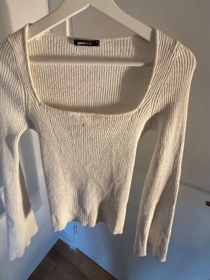 Vit ribbstickad tröja Gina Tricot - Säljer en vit ribbstickad tröja från Gina Tricot med fyrkantig urringning och långa ärmar. Tröjan har en tight passform och är gjord i mjukt stickat material, perfekt för lager på lager och en clean look.