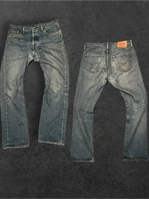 Feta Levi’s jeans Staight passform - Klassiska blå Levi's jeans med rak passform och fem fickor. Jeansen har slitna detaljer, knappgylf och tydliga kontrastsömmar. Tillverkade i robust denim med vintagekänsla och ikonisk läderpatch bak i midjan.