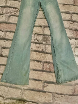 Ljusblå bootcut jeans - Säljer ett par ljusblå bootcut jeans med utsvängda ben och slitningar framtill. Jeansen har klassisk femficksdesign och är tillverkade i denim. Perfekta för dig som gillar retrostil och vill ha ett par riktigt snygga jeans med 70-talsvibbar.