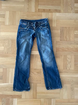 Blå bootcut jeans med slitningar - Säljer dessa ”y2k” jeans som inte kommer till användning så mycket. Köpte dem i somras men har använts 5 gånger åtminstone, skriv jätte gärna ifall ni vill ha mått eller bilder! Kan även tänka mig sälja för lite mindre!!