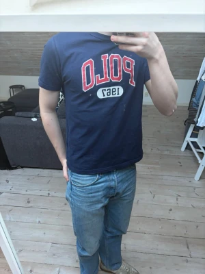 Mörkblå Polo Ralph Lauren t-shirt - Säljer en mörkblå t-shirt från Polo Ralph Lauren. Klassisk passform och rund halsringning. Perfekt för dig som gillar stilrena och sportiga plagg. Den är i gott skick och har inga defekter.