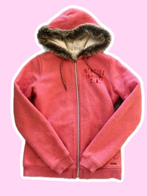 Rosa hoodie från O'Neill med fuskpäls - Säljer en rosa hoodie från O'Neill med fjäder dragkedja och mysig huva fodrad med fuskpäls med tryck på ena sidan. Perfekt för chill dagar eller lite y2k/Mcbling. Materialet är mjukt och skönt, troligen bomullsblandning. Skriv för mer info eller bilder, pris är diskuterbart 💞🪶!