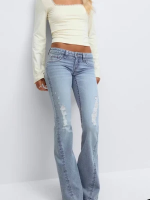 Blå coola bootcut jeans Gina Tricot - Säljer ett par blå bootcut jeans från Gina Tricot med slitningar och hål på låren. Jeansen är i storlek 152🫶Coola o fräcka rosa/röda detaljer på både fram o bak sida!