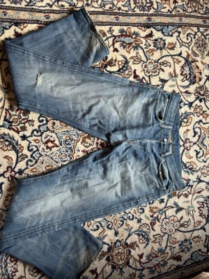 Raplh lauren jeans - Säljer ett par blå jeans med raka ben och slitningar på låret. Jeansen har klassisk passform och ljus tvätt med tydliga slitningar. Storlek w32 l34.